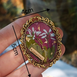 Detailed view of handmade oval resin brooch with real flowers and gold foil, 4cm x 5cm size