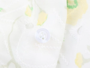 Close-up of white floral dress fabric with yellow print and elegant button detail