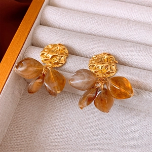 Detailed shot of retro resin drop earrings with gold textured discs and amber beads