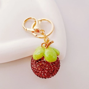 Detailed close-up of sparkling rhinestone-studded lychee fruit keychain with gold hardware