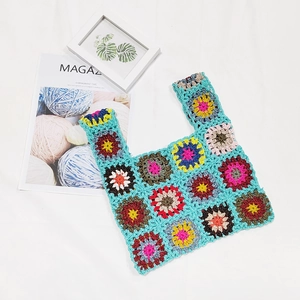 Detailed close-up of handmade granny square crochet bag with colorful floral patterns