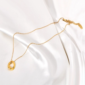 Collier doré minimaliste avec pendentif ovale irrégulier sur fond de soie blanche douce