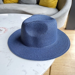 Close-up of dark blue woven sun hat with fine texture on white marble table surface