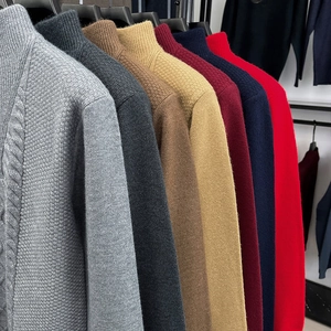 Detailansicht strukturierter Zopfstrickpullover in diversen Farben an schwarzen Kleiderbügeln
