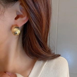 Chic golden geometric C-shape stud earrings with hammered metal texture on model