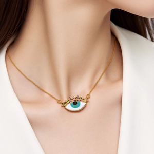 Close-up of golden Evil Eye necklace with colorful cubic zirconia worn by a model