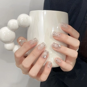 Detailed view of nude pink press-on nails with silver polka dots and 3D bow charms