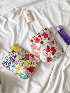 Detailed top view of two vintage floral cotton makeup bags with zippers on white fabric