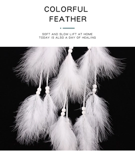 Detailed view of delicate white feathers and small beads on a handmade dream catcher