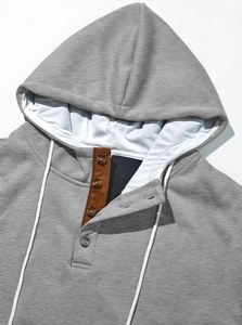 Détail d'un sweat à capuche gris montrant quatre boutons et patte en velours côtelé