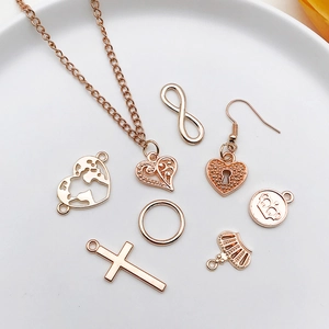 Rose gold jewelry set with heart, cross, and crown pendants on a white ceramic plate