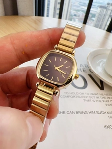 Close-up of golden square watch with dark dial on a wrist in a cozy setting
