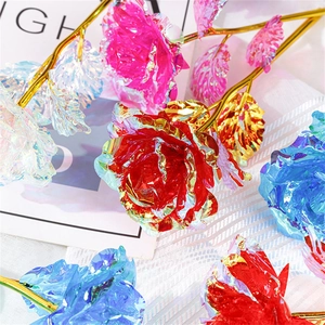 Macro detail of iridescent colorful foil roses with golden stems on white textured cloth