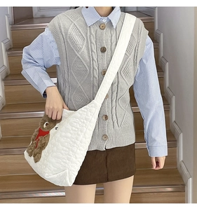 Close-up of a white quilted tote bag featuring a cute brown plush bear charm detail