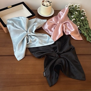 Lustrous satin square scarf hair ties in pastel blue, pink, and black on a wooden table