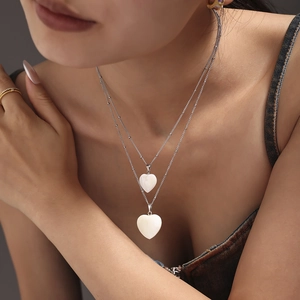 Zweilagige silberne Edelstahlkette mit zwei weißen Herzmuschel-Anhängern an einem Modell