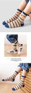 Detail of striped mesh baby socks featuring navy stripes and dinosaur letter embroidery