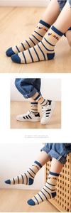 Detail of striped mesh baby socks featuring navy stripes and dinosaur letter embroidery