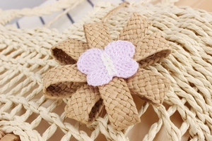 Macro detail of bohemian floral ornament with crochet butterfly on a woven bag