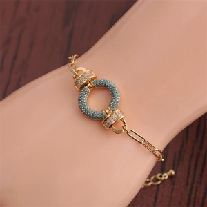 Detail of gold paperclip bracelet with turquoise stone ring and clear cubic zirconia