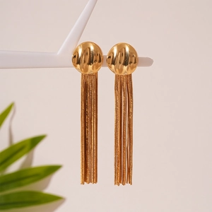 Elegant gold fringe tassel earrings hanging on a white jewelry stand with soft background