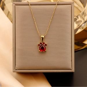 Détail du collier à billes dorées avec pendentif patte en forme de cœur rouge
