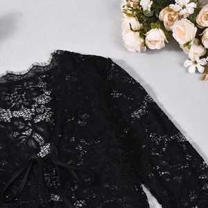 Close-up of black floral lace top featuring delicate eyelash trim and front tie detail