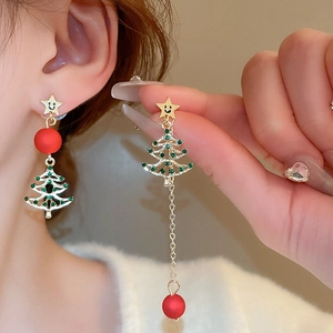 Dettaglio di orecchini natalizi asimmetrici con albero di strass e perle rosse sul modello