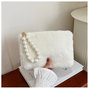 Detail of white plush handbag featuring elegant pearl handle and soft faux fur texture