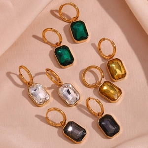 Detailed close-up of 18K gold earrings with rectangular zircon drops on silk