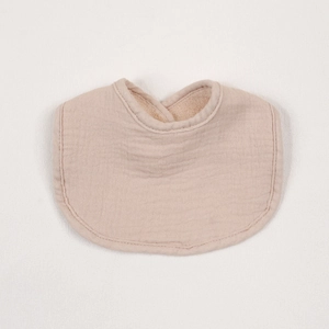 Close-up of soft muslin cotton baby bib in beige color with absorbent fleece lining