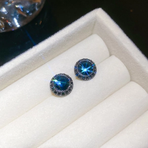 Macro shot of dark blue round zircon earrings with black crystal pave on jewelry tray