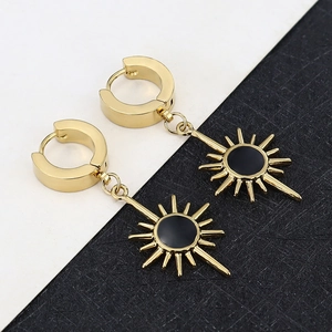 Detail of gold huggie earrings with sunburst charms and black enamel inlay for modern look