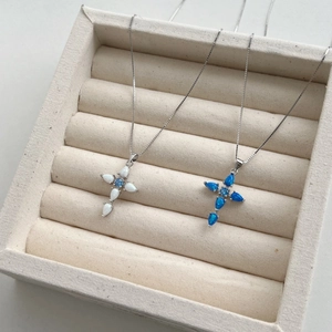 Close-up of S925 sterling silver cross pendants with white and blue opal in a jewelry box