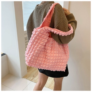 Pink bubble textured shoulder tote bag shown on model in a minimalist indoor setting