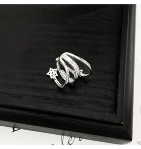 Detail of silver multi-layer ear cuff with black zircon stars on dark wooden surface