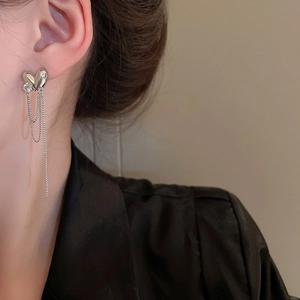Close-up of model wearing silver tassel earrings with delicate chains and zircons