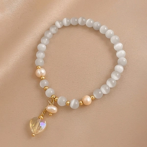 Détail du bracelet en perles d'oeil de chat et cristal de cœur sur de la soie