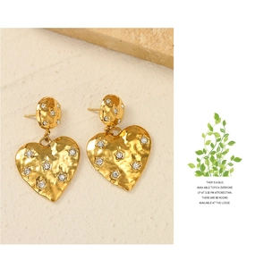 Detail of 14k gold heart earrings with hammered texture and star-shaped crystals