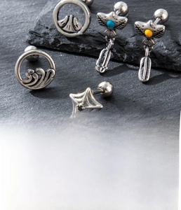 Macro detail of vintage silver stainless steel earrings with eagle feather and star designs