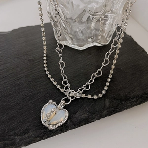Detail of silver double-layered heart necklace with opal and pavé zircon stones