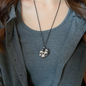 Dettaglio del ciondolo geometrico in argento su un cordoncino nero indossato da una modella
