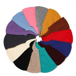 Flat lay of knit beanies in 14 vibrant colors arranged in a creative circular layout