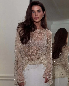 Close-up of beige hollow knit sweater with shiny silver sequins and open mesh texture
