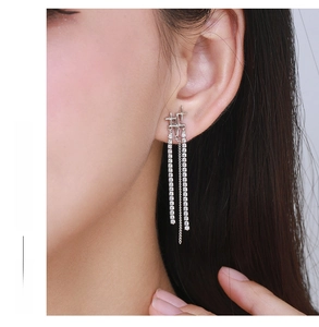 Detail of silver tassel earrings with crystal cross on model showing elegant movement
