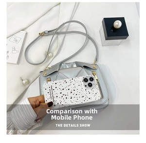 Silver metallic crossbody bag with gold zippers shown next to a phone for size comparison