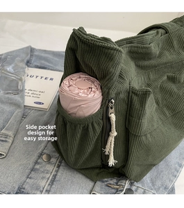 Détail de la poche latérale d'un sac cabas en velours vert contenant un parapluie rose