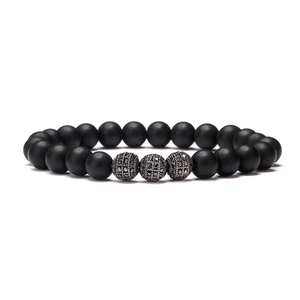 Makroaufnahme von matt-schwarzem Perlenarmband mit drei funkelnden Zirkonia-Kugeln