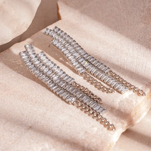 Détail macro de boucles d'oreilles argentées avec zircons baguette et pampilles fines