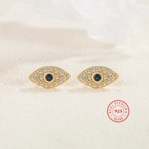 Macro detail of 925 sterling silver evil eye stud earrings with blue gems and white zircon